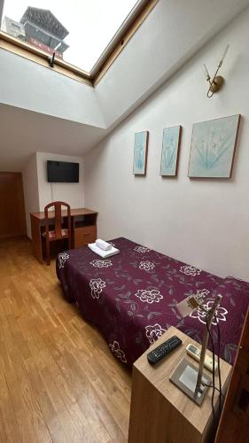 1 dormitorio con cama y mesa con mando a distancia en H. LAVID, en Briviesca