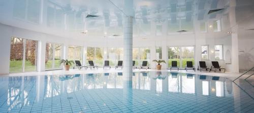 a large swimming pool in a building with chairs at Koetshuis Landgoed Lauswolt in Beetsterzwaag
