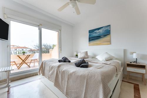 ein weißes Schlafzimmer mit einem Bett und einem großen Fenster in der Unterkunft Villa in Los Flamencos in Sitio de Calahonda