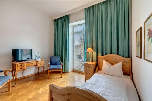 a bedroom with a bed and a desk and a television at Hotel Kolbergarten in Bad Tölz