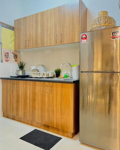 a kitchen with a stainless steel refrigerator and wooden cabinets at Alanis Suite With Netflix @ KLIA Sepang in Sepang