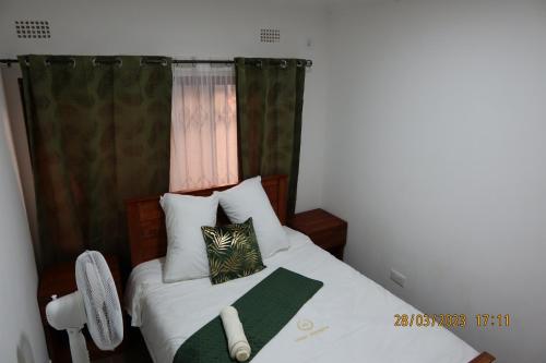 a bedroom with a bed with a green curtain at Katonga Lolani Apartment in Lusaka