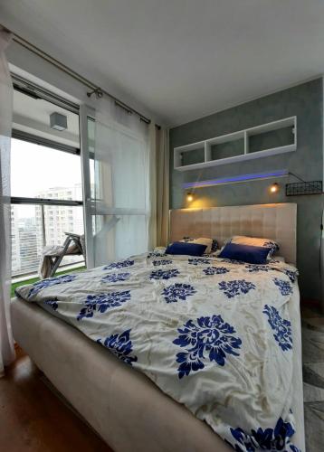 a bedroom with a bed with a blue and white comforter at Przestronny Apartament Happy 7 in Warsaw