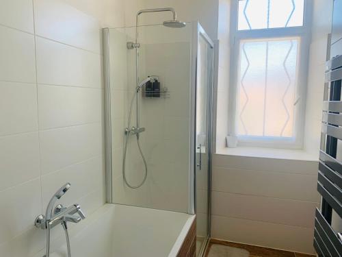 a shower with a glass door in a bathroom at Les Volets Rouges in Saint-Sauveur-de-Cruzières