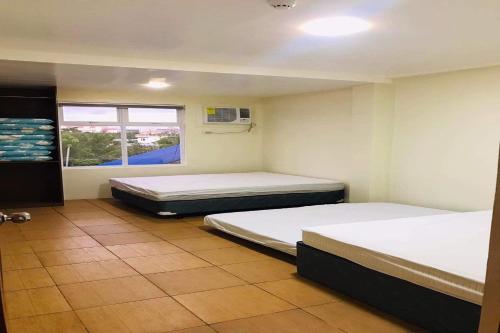 two beds in a room with a window at I'm Inn Hotel Sorsogon near SM or Terminal in Sorsogon