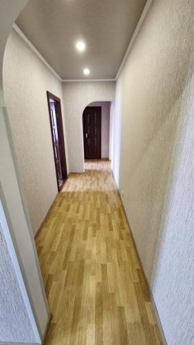 un corridoio vuoto con pavimento in legno in una casa di Трикімнатна квартира зі всіма зручностями a Vilʼshanka