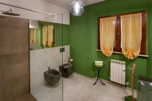 baño con paredes verdes y ducha de cristal en Locanda del sorriso b&b, en San Quirico dʼOrcia