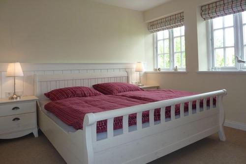 a bedroom with a large white bed with red pillows at Alte Eiche in Utersum