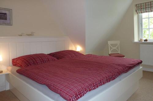 a bed with a red comforter in a bedroom at Alte Eiche in Utersum