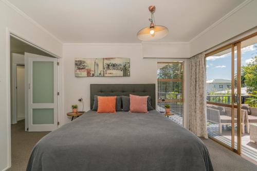 a bedroom with a large bed and a balcony at Oceans 88 Whitianga Coastal Suites in Whitianga