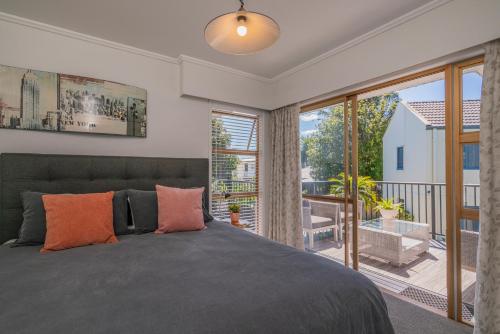 a bedroom with a large bed and a balcony at Oceans 88 Whitianga Coastal Suites in Whitianga