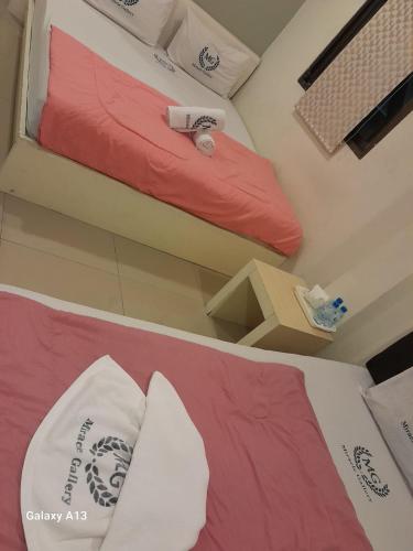 a bedroom with two beds with red and white sheets at Miracle Gallery Hotel in Makkasan