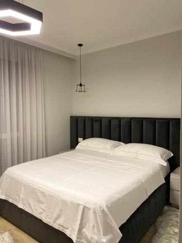 1 dormitorio con 1 cama grande con sábanas blancas en Honey Suite, en Tirana