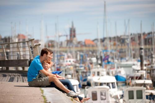 a man and a woman sitting on a pier near a marina at Holiday Suites Blankenberge in Blankenberge