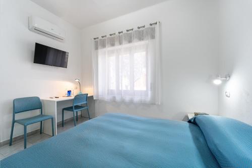 a white bedroom with a blue bed and a desk at Trivano il Rifugio in Carbonia