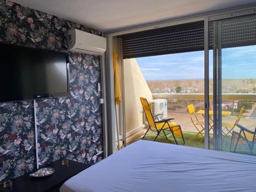 - une chambre avec un lit, une télévision et un balcon dans l'établissement Studio Héliopolis L Village Naturiste, au Cap d'Agde
