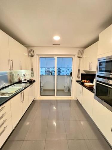 a large kitchen with white cabinets and a large window at Becas House - Lisboa in Lisbon