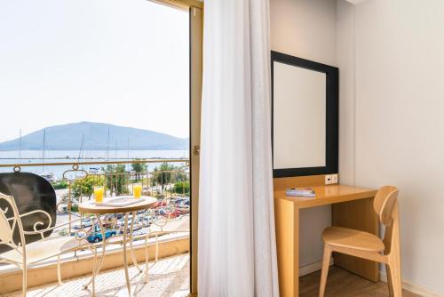 a room with a balcony with a table and a window at Hotel Lefkas in Lefkada Town