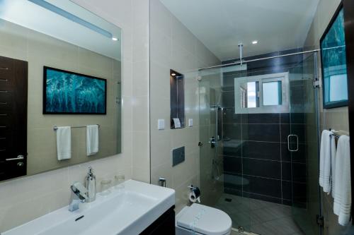 a bathroom with a sink and a shower and a toilet at Aura Suites in Dar es Salaam