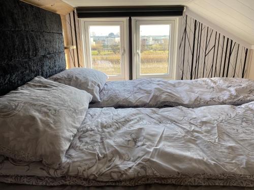 an unmade bed in a bedroom with two windows at Chapel Fields Holiday Park in Chapel Saint Leonards