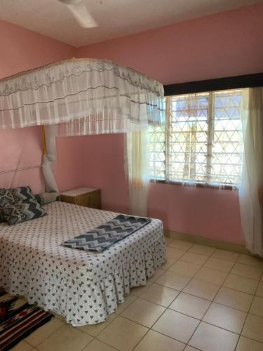 a bedroom with a canopy bed and a window at ZURI Homestay WIFI & Ocean BREEZE !! in Mombasa