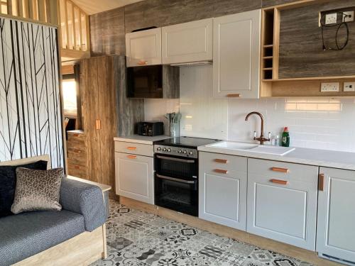 a kitchen with white cabinets and a sink and a stove at Chapel Fields Holiday Park in Chapel Saint Leonards
