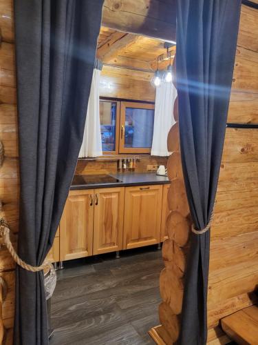 una cocina con cortinas azules en una cabaña de madera en БЕРЕЗИНИ, 