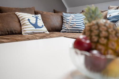 a couch with pillows and a pineapple on a table at Haus Strandwinkel Ferienwohnung "Strandwinkel 1" in Scharbeutz