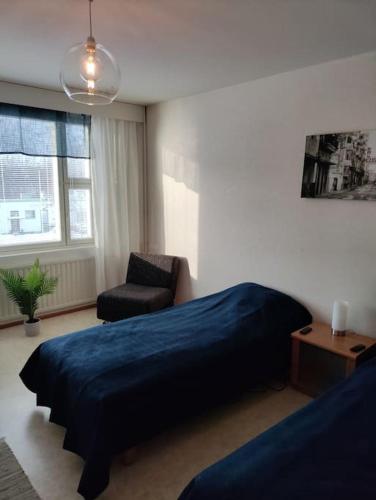 een slaapkamer met een blauw bed en een stoel bij Toimiva kodikas yksiö in Heinola