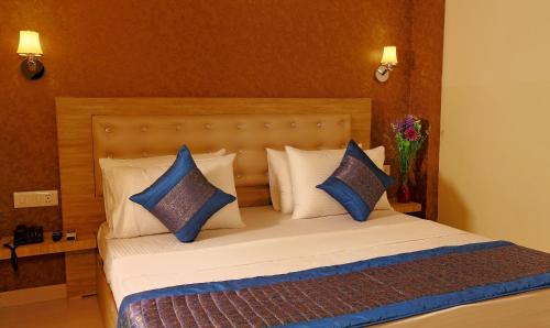 a bedroom with a bed with blue and white pillows at Hotel Aeroporto in New Delhi
