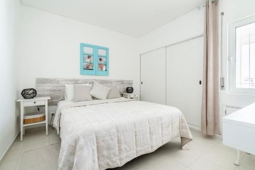 a white bedroom with a large bed and a window at Praia Mar in Quarteira