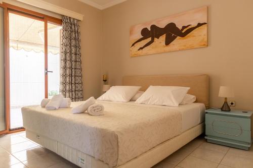 a bedroom with a bed with white sheets and a window at Bolero Apartment Argostoli in Argostoli