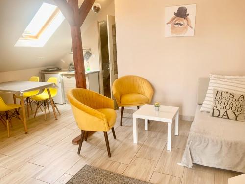a living room with yellow chairs and a table at Lelle -kert Apartman 03 in Balatonlelle