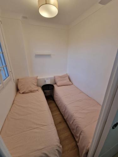 deux lits dans une petite pièce avec une fenêtre dans l'établissement Nid douillet en bord de mer, à Argelès-sur-Mer