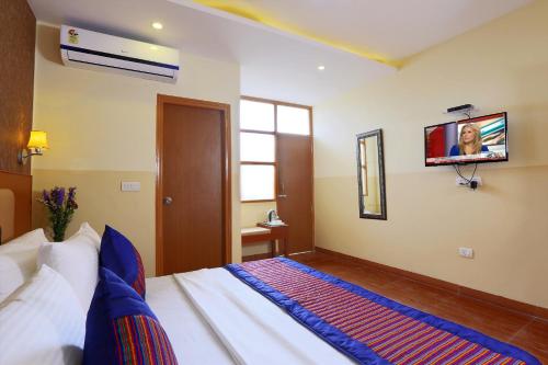 a bedroom with a bed with a tv on the wall at Hotel Aeroporto in New Delhi