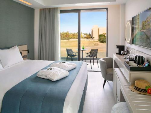a hotel room with a bed with two towels on it at Mercure Larnaca Beach Resort in Larnaca