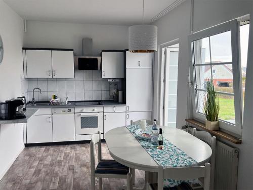 a kitchen with white cabinets and a table with chairs at Ferienhäuser Insel Usedom Haus Diego 9 - Blick aufs Achterwasser! Whirlpool und Sauna in Lütow