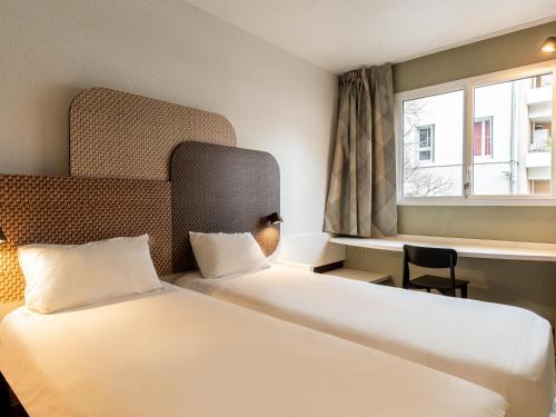 um quarto de hotel com duas camas e uma janela em B&B HOTEL Marseille Prado Parc des Expositions em Marselha