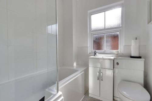 a white bathroom with a toilet and a bath tub at Beautiful, 3 Bedroom Terrace, 2 minutes walk from Chester train station. in Chester