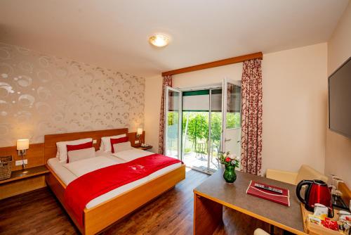 a bedroom with a bed with a red blanket at Hotel Garni Weinquadrat in Weissenkirchen in der Wachau