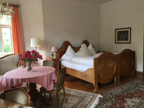 a bedroom with a bed and a table with a vase of flowers at Hotel Kolbergarten in Bad Tölz