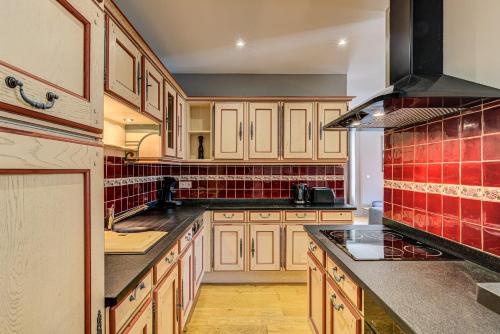 une cuisine avec des placards en bois et du carrelage rouge dans l'établissement APARTMENT PRESIDENT - Alpes Travel - Central Chamonix - Sleeps 12, à Chamonix-Mont-Blanc