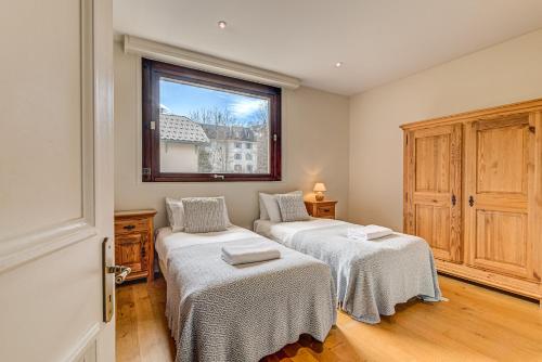 two beds in a room with a window at APARTMENT PRESIDENT - Alpes Travel - Central Chamonix - Sleeps 12 in Chamonix-Mont-Blanc