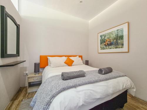 a bedroom with a large bed with an orange pillow on it at The beachclub 17 in Hout Bay