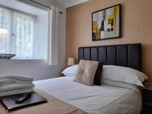 a bedroom with a large white bed with a black headboard at Thurlestone House in St Ives