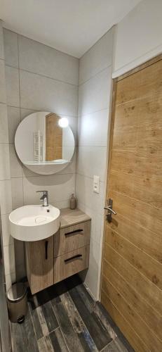 ein Badezimmer mit einem Waschbecken und einer Holztür in der Unterkunft Maisons 2 Chambres tout confort. in Cérans-Foulletourte