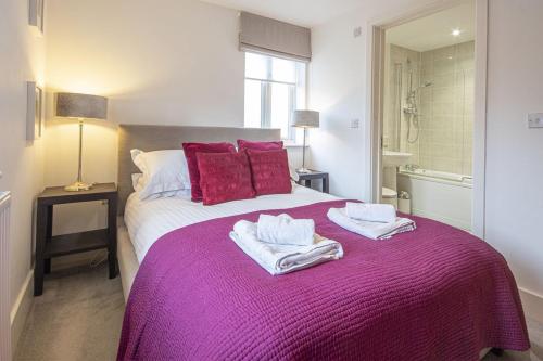 a bedroom with a purple bed with towels on it at Howells Mere 88, Tranquility P in Somerford Keynes