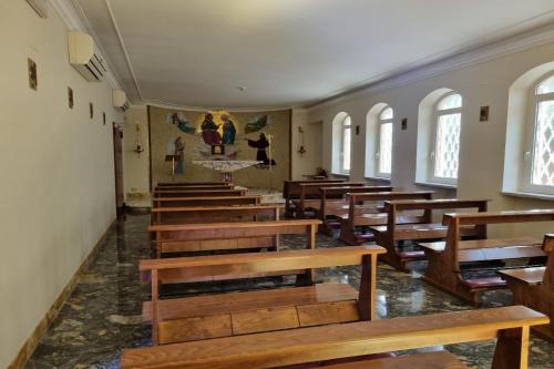 an empty church with wooden benches in a room with windows at Palazzo Sant'Antonio in Rome