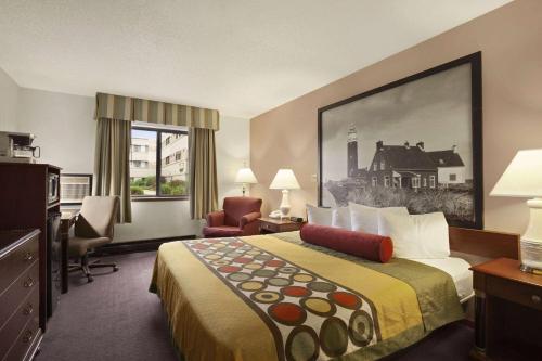 um quarto de hotel com uma cama, uma secretária e uma cadeira em Super 8 by Wyndham Milwaukee Airport em Milwaukee