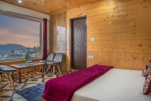 a bedroom with a bed and chairs and a window at Mountain View New Kufri in Cheog